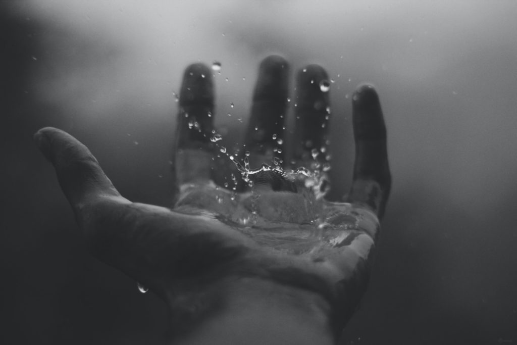 Mano con la palma hacia arriba con agua salpicando